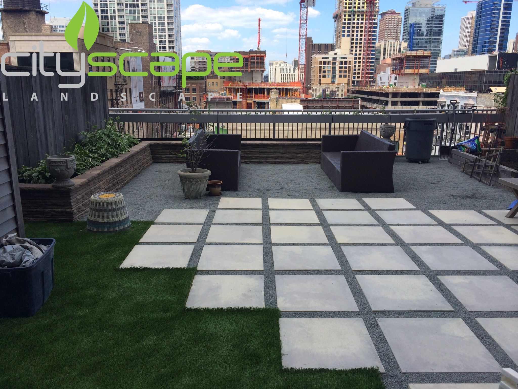 A patio area with grass, benches, and potted plants